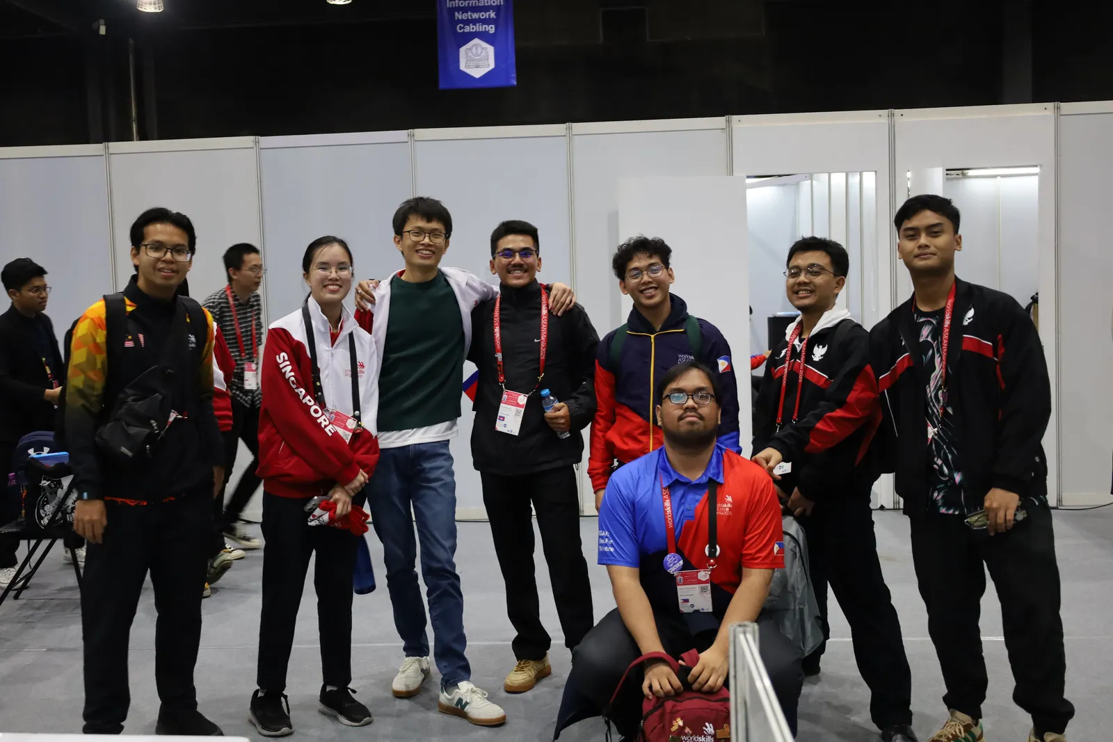 Competitors from several countries, including Singapore, Indonesia and the Philippines, posing together on the WorldSkills ASEAN Manila 2025 competition floor