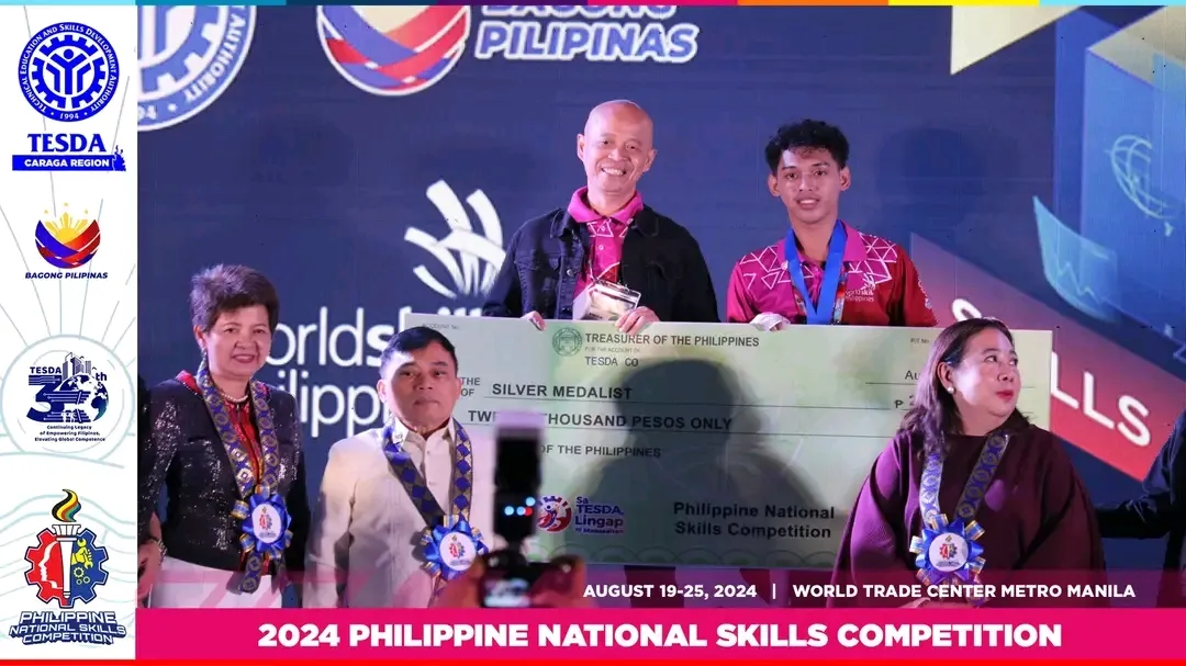 Joshi holding the oversized Silver Medalist cheque on stage at the 2024 Philippine National Skills Competition