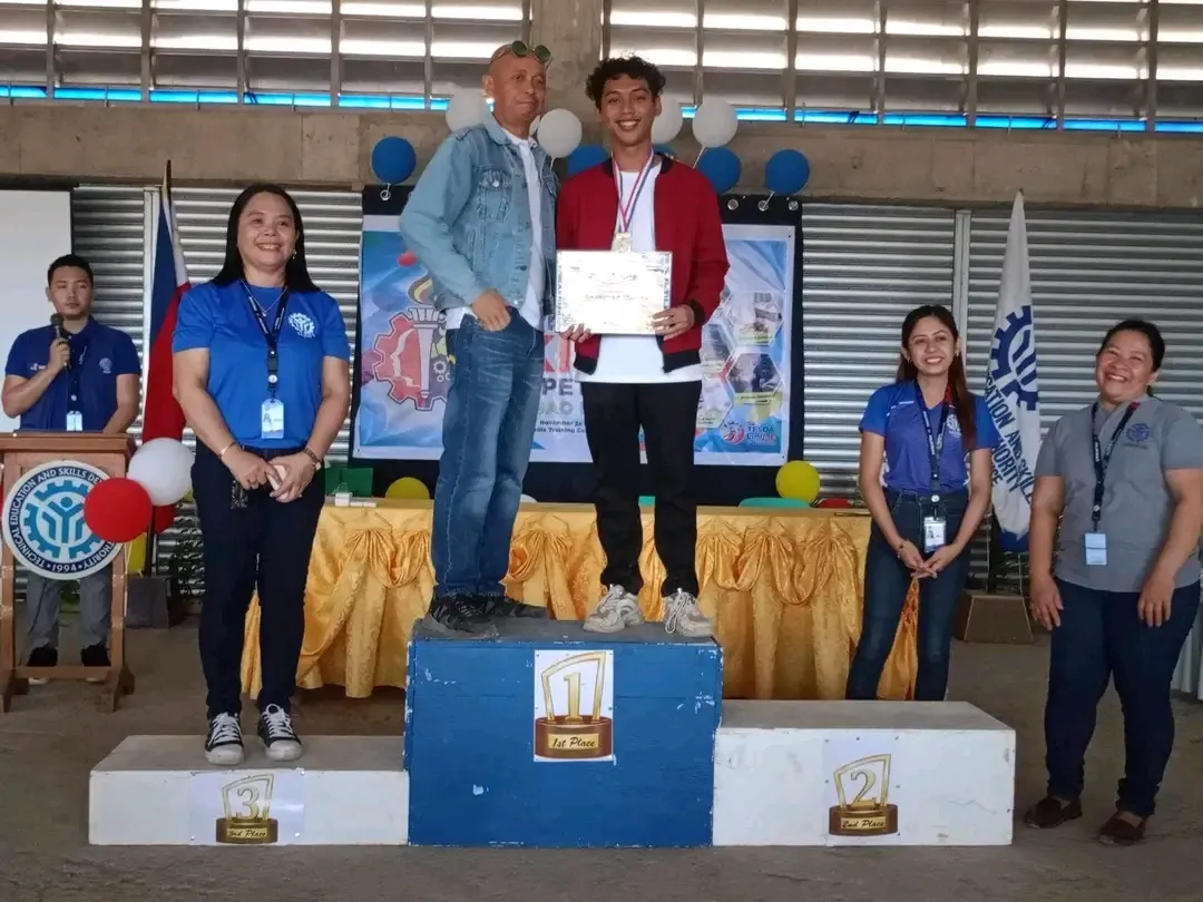 Joshi on the first-place podium holding a certificate, with TESDA officials on either side